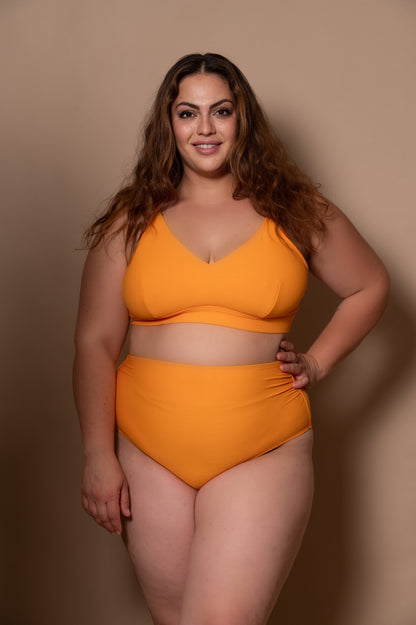 plussize woman wearing a yellow bikini against a beige background