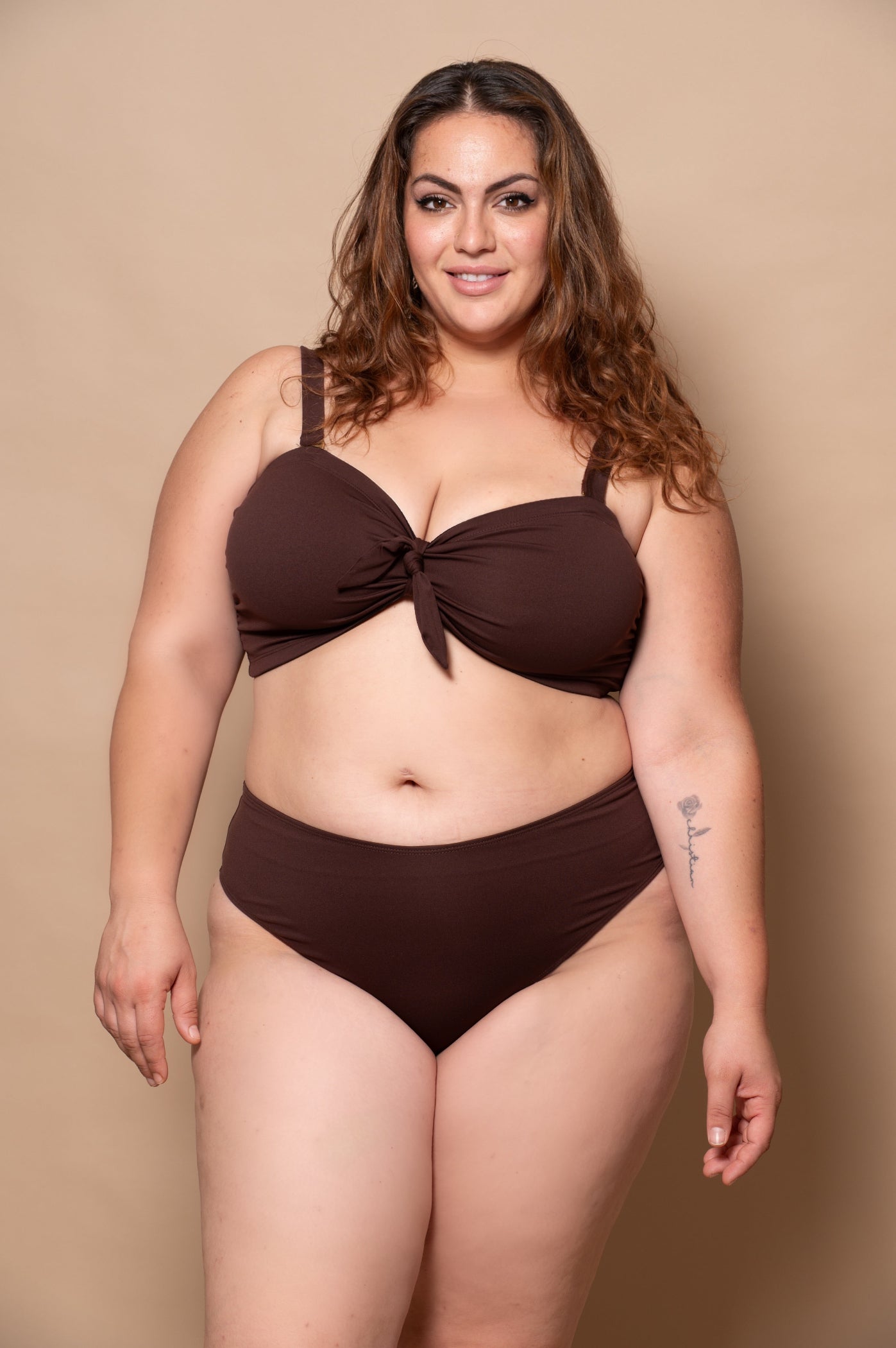 plussize woman wearing a chocolate brown bikini set against a beige background