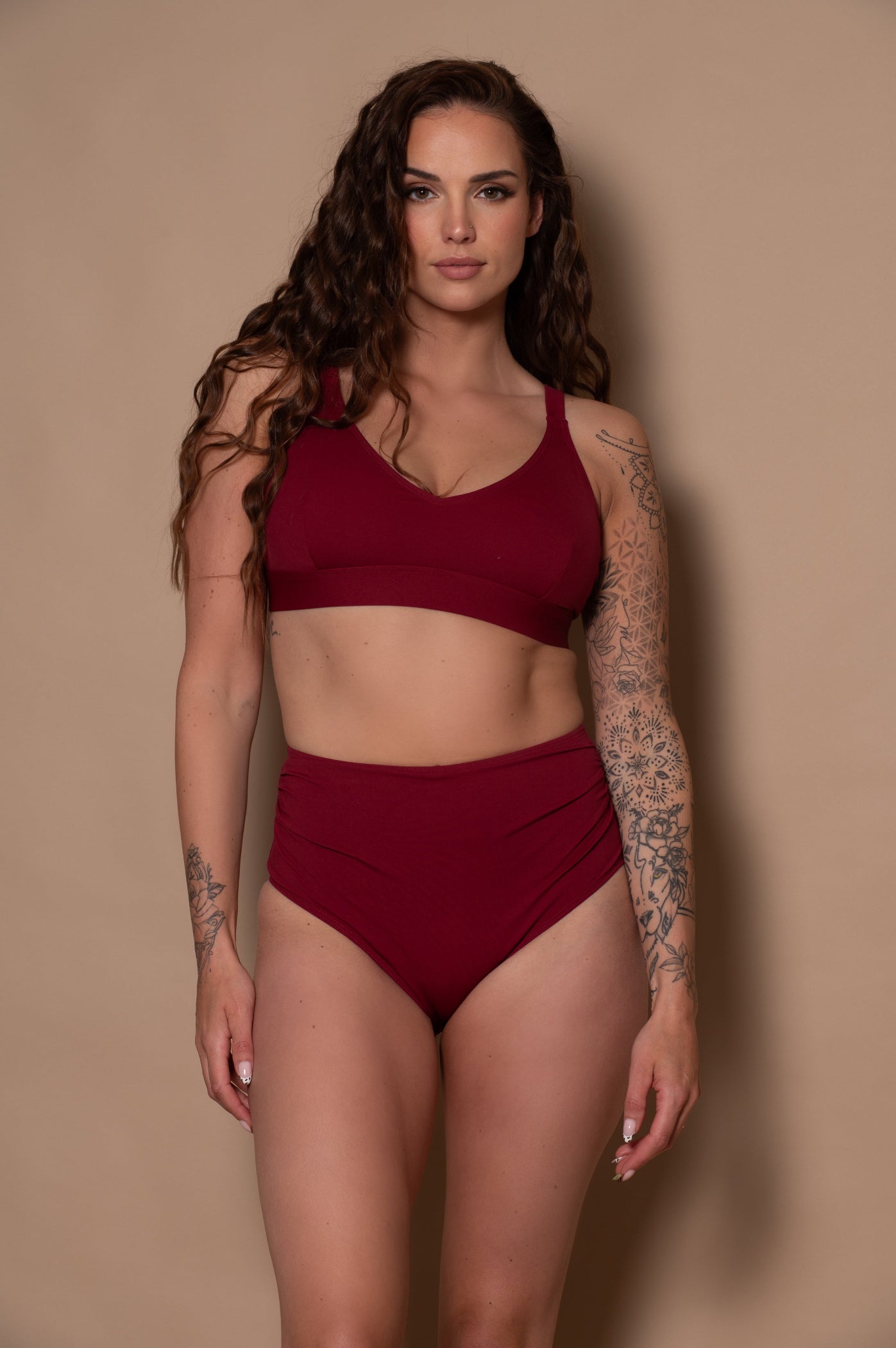 woman wearing a wine red bikini against a beige background