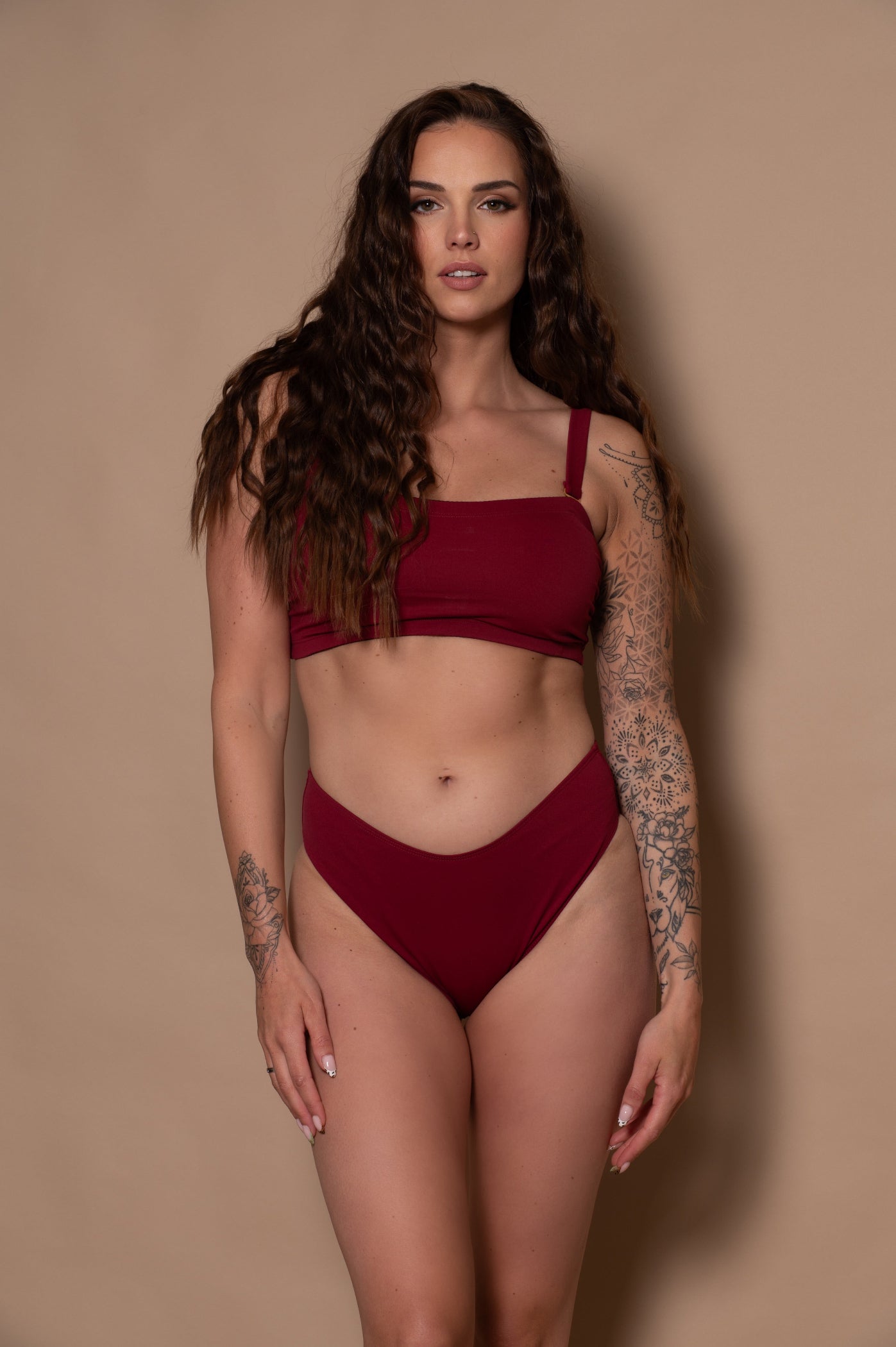 woman wearing a wine red bikini against a beige background