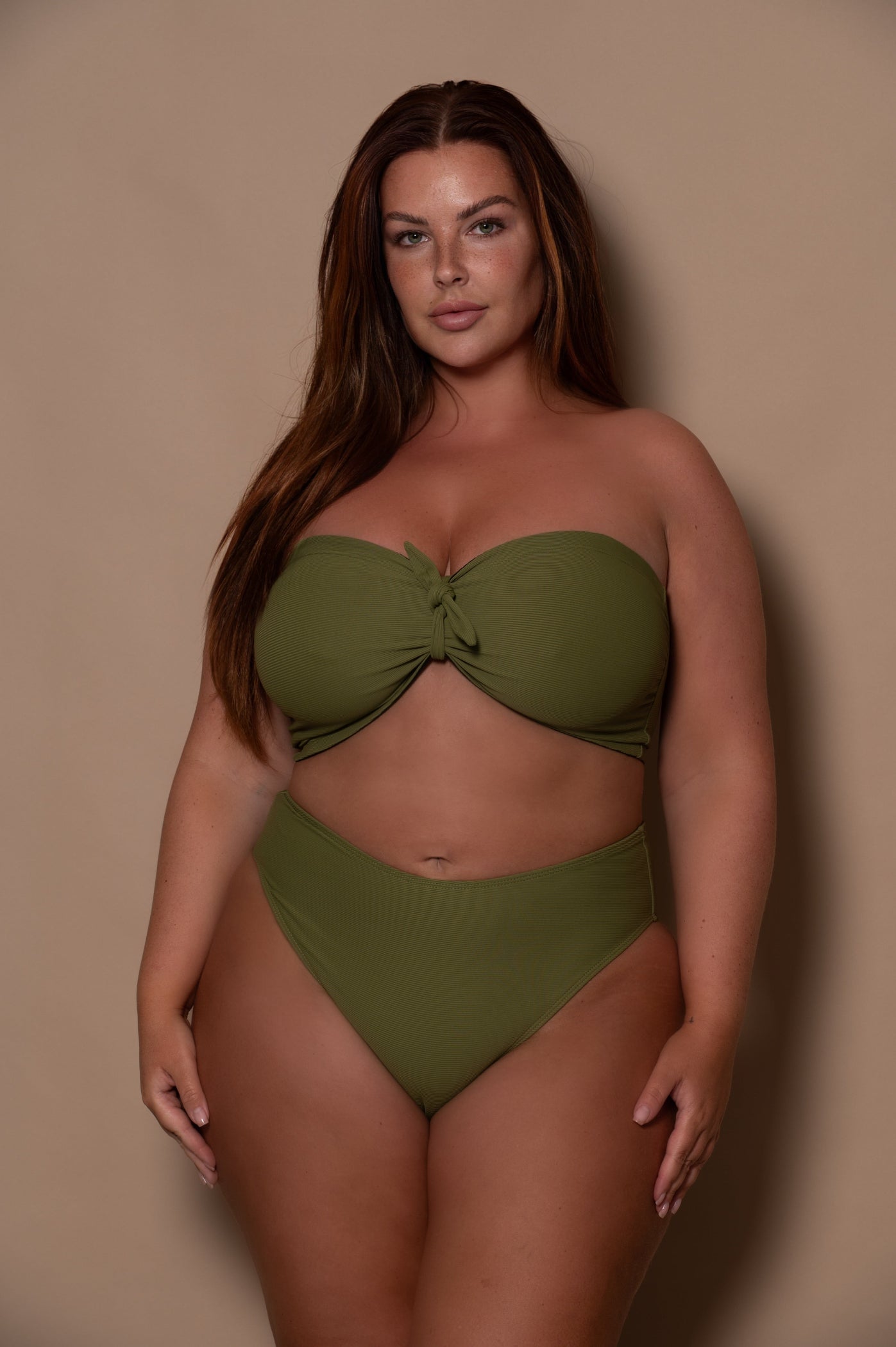 plussize woman wearing a green khaki bikini against a beige background