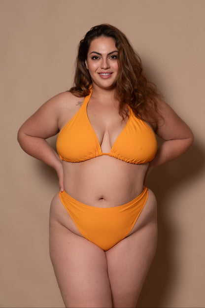 plussize woman wearing a yellow bikini against a beige background