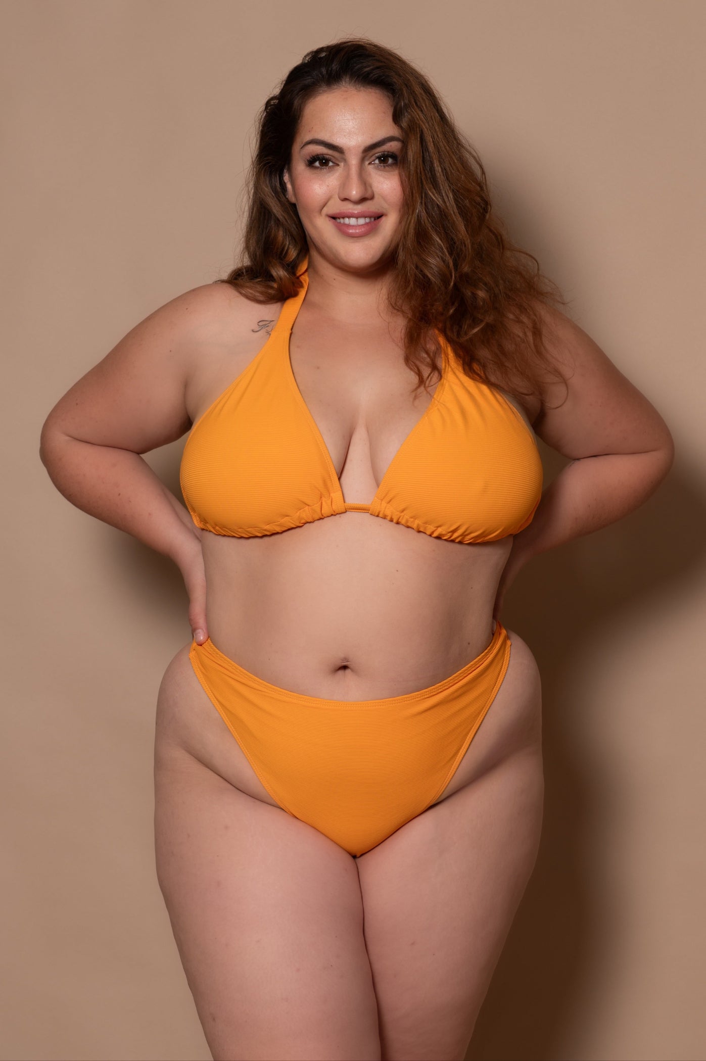 plussize woman wearing a yellow bikini  against a beige background