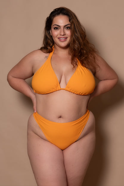 plussize woman wearing a yellow bikini  against a beige background