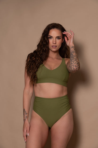 woman wearing a green - khaki  bikini against a beige background