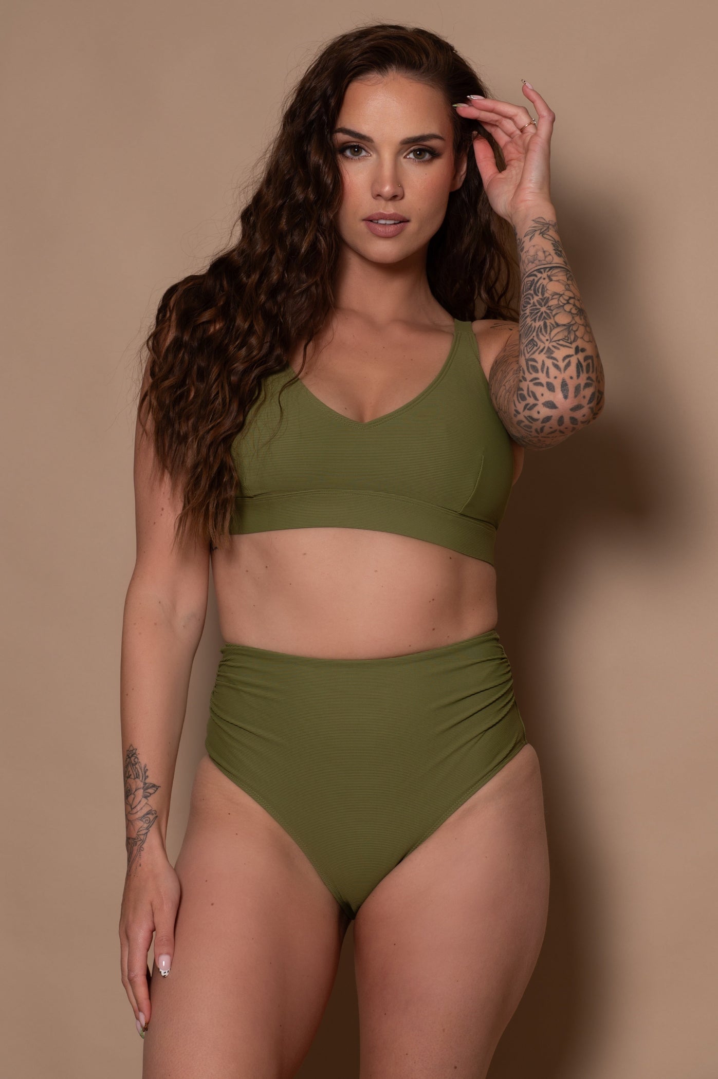 woman wearing a khaki green bikini  against a beige background