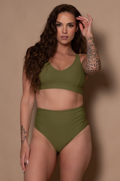 woman wearing a khaki green bikini  against a beige background