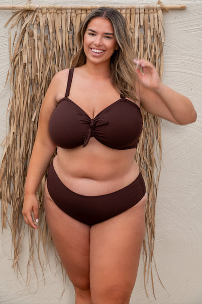 plussize woman wearing a chocolate brown bikini  against a beige background