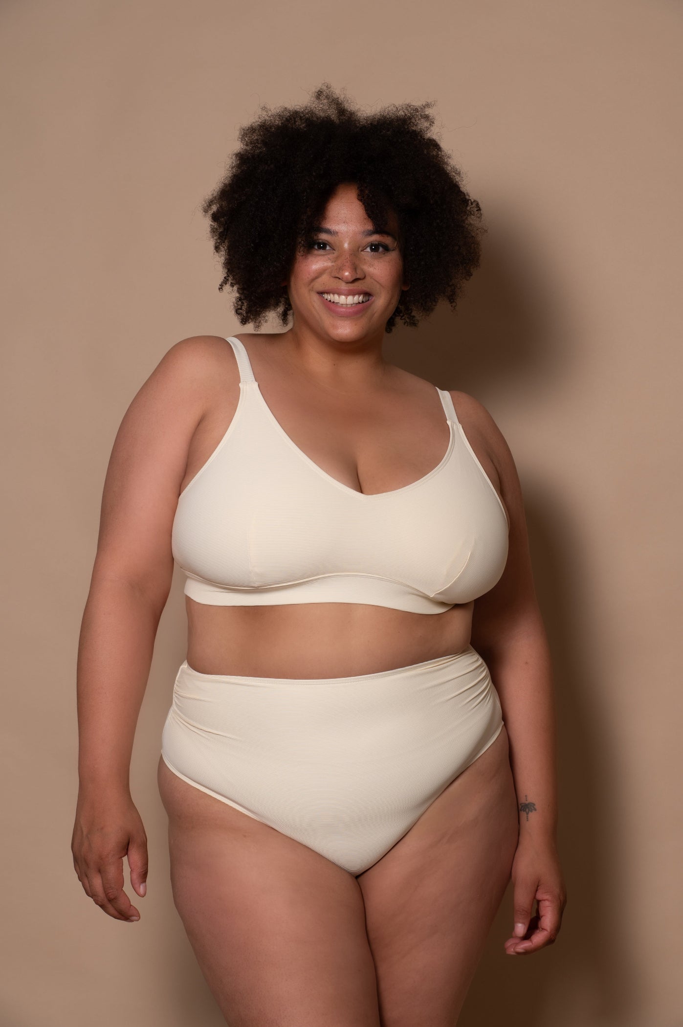 curvy woman wearing a cream - white  bikini against a beige background