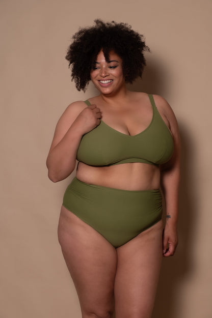 curvy woman wearing a green - khaki  bikini against a beige background