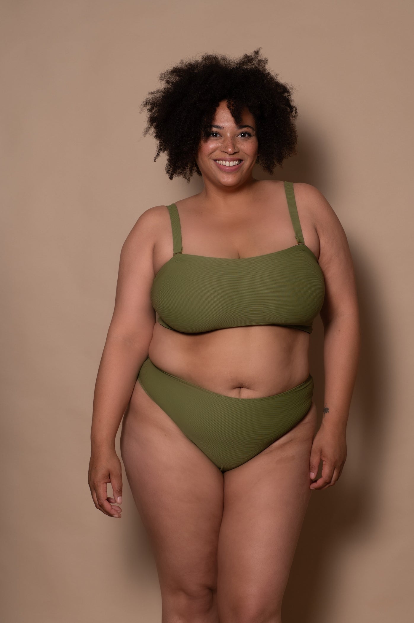 plussize woman wearing a green khaki bikini against a beige background