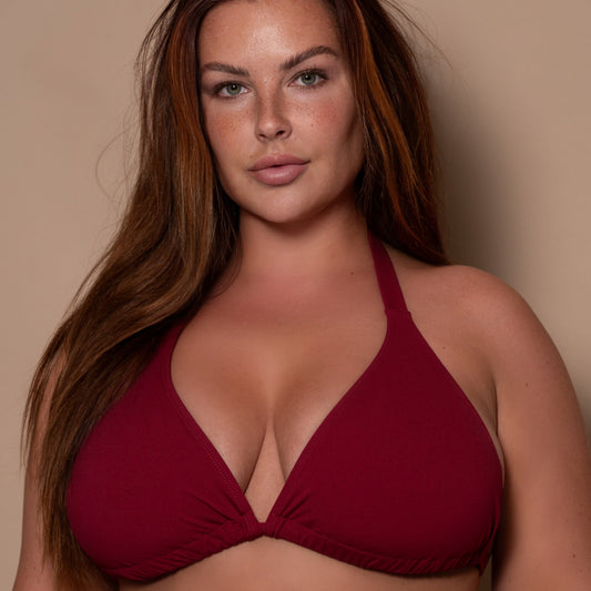 plussize woman wearing a pomegranate red bikini  against a beige background