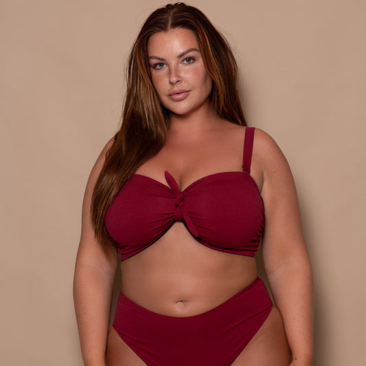 plussize woman wearing a pomegranate red bikini  against a beige background