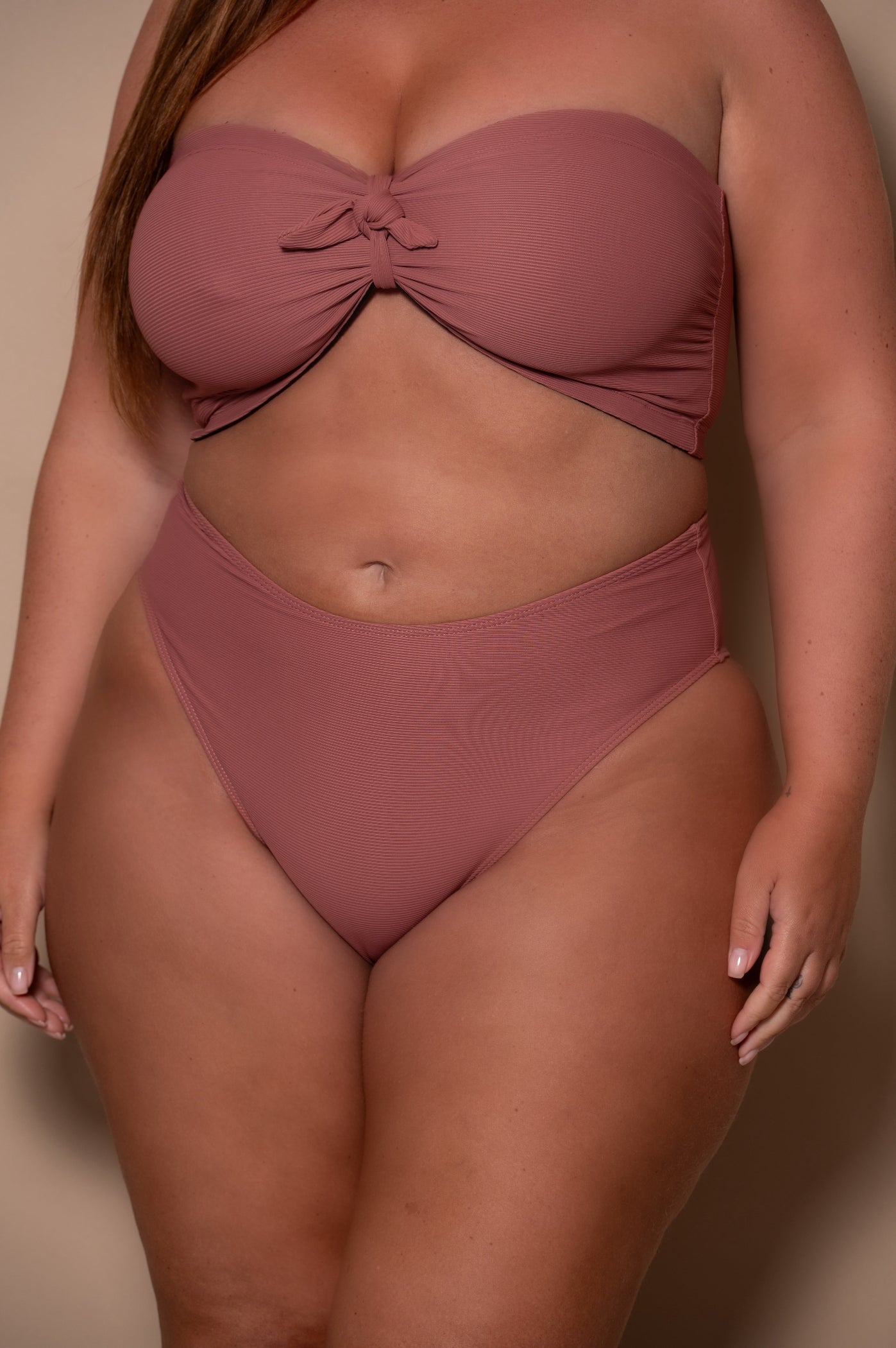 plussize woman wearing a rosewood bikini against a beige background