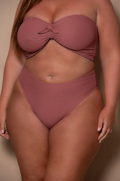 plussize woman wearing a rosewood bikini against a beige background