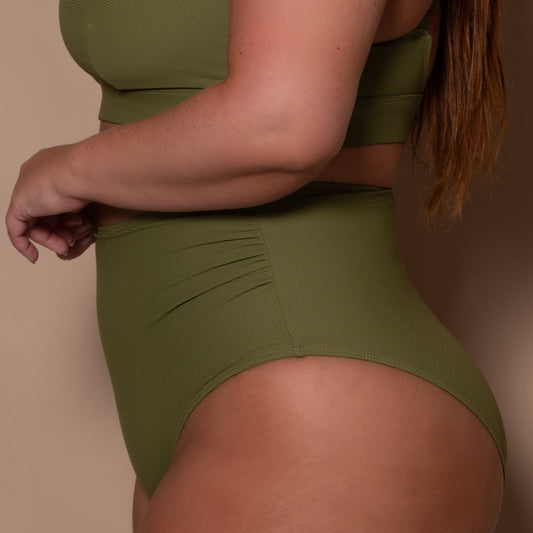 plussize woman wearing a khaki green high waist bikini  against a beige background