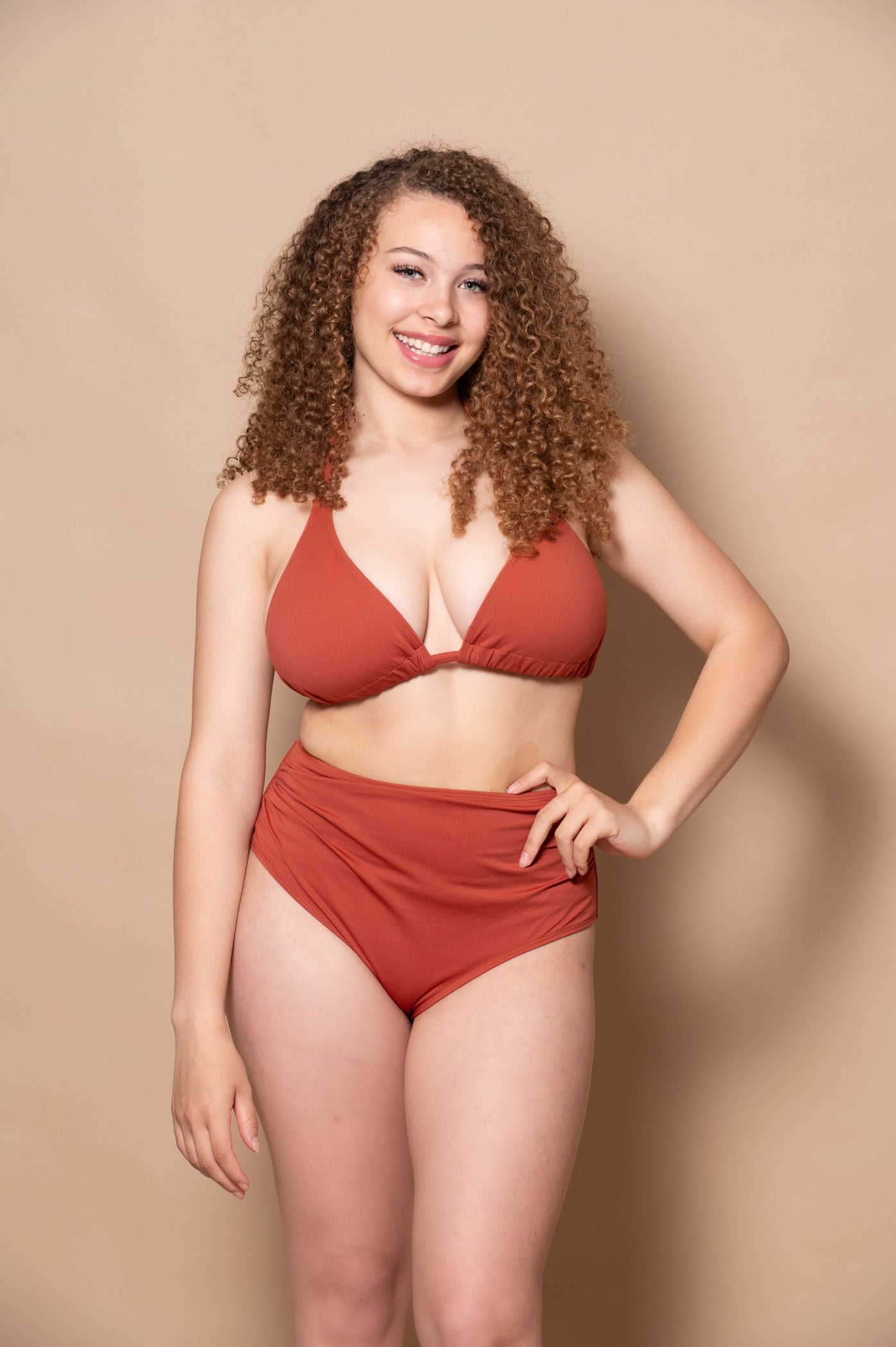woman wearing a rust red bikini  against a beige background