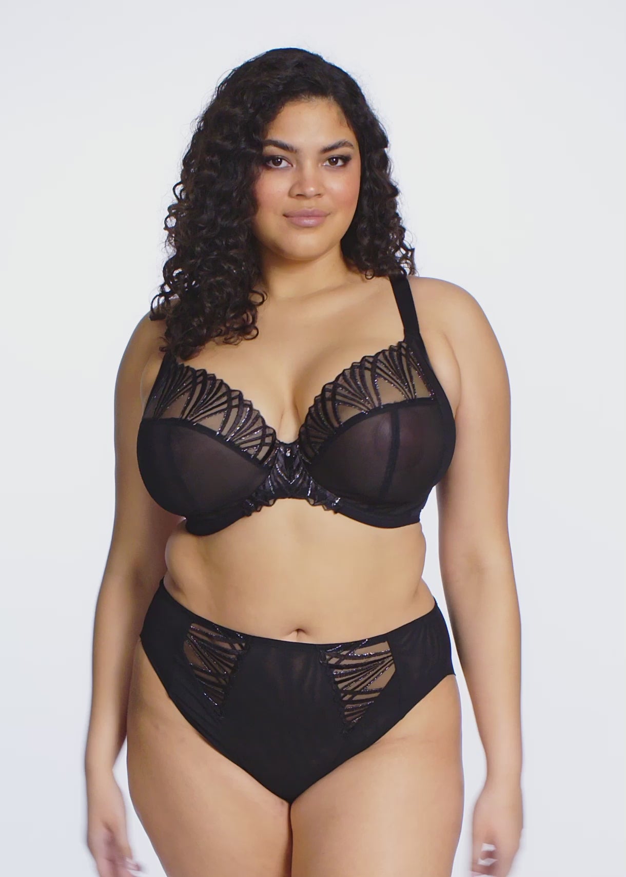 curvy woman wearing black lingerie with geomatric lace pattern against a white background