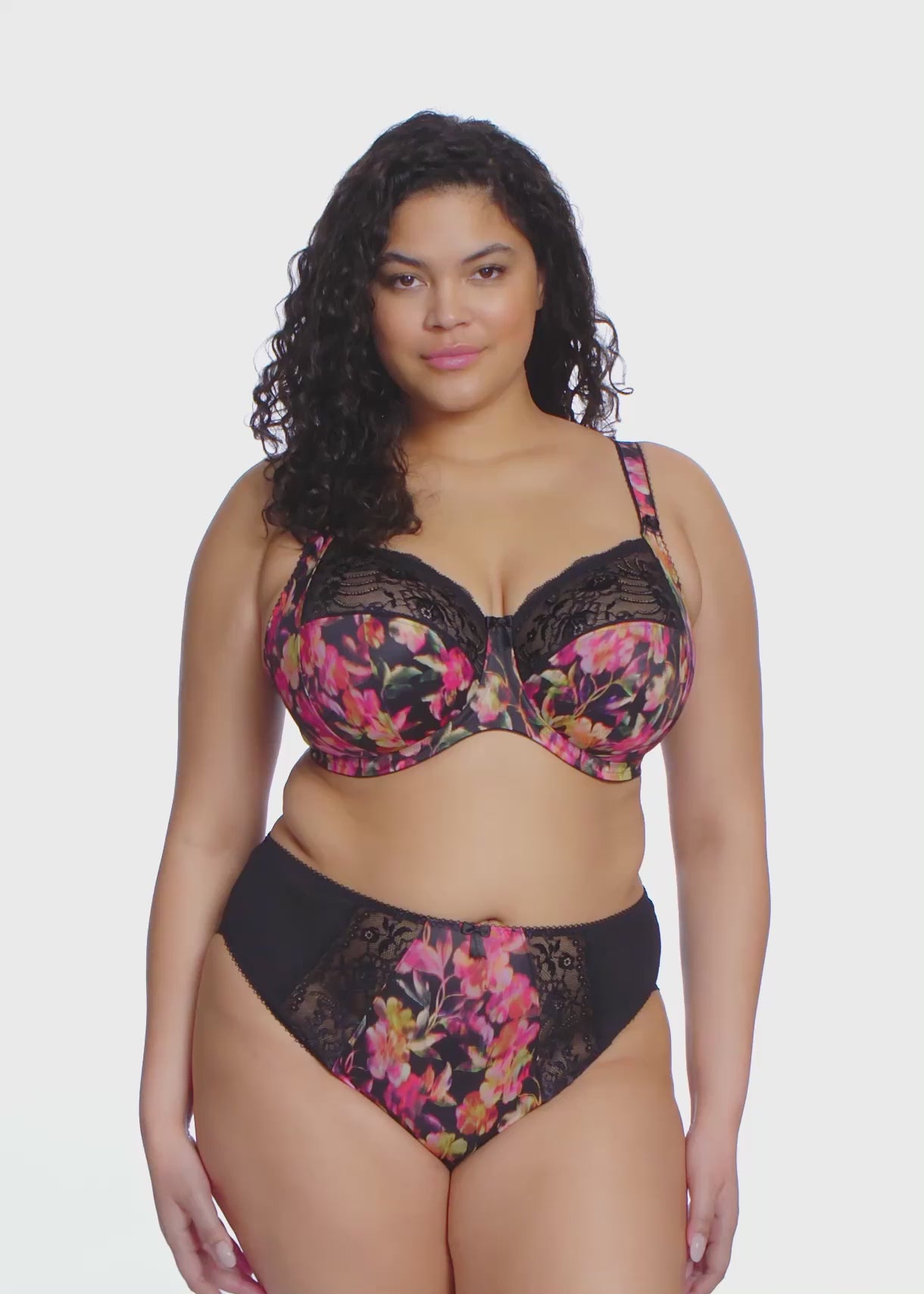 curvy woman wearing a plussize bra in black with colourfull printed flowers and stretch lace  and matching briefs