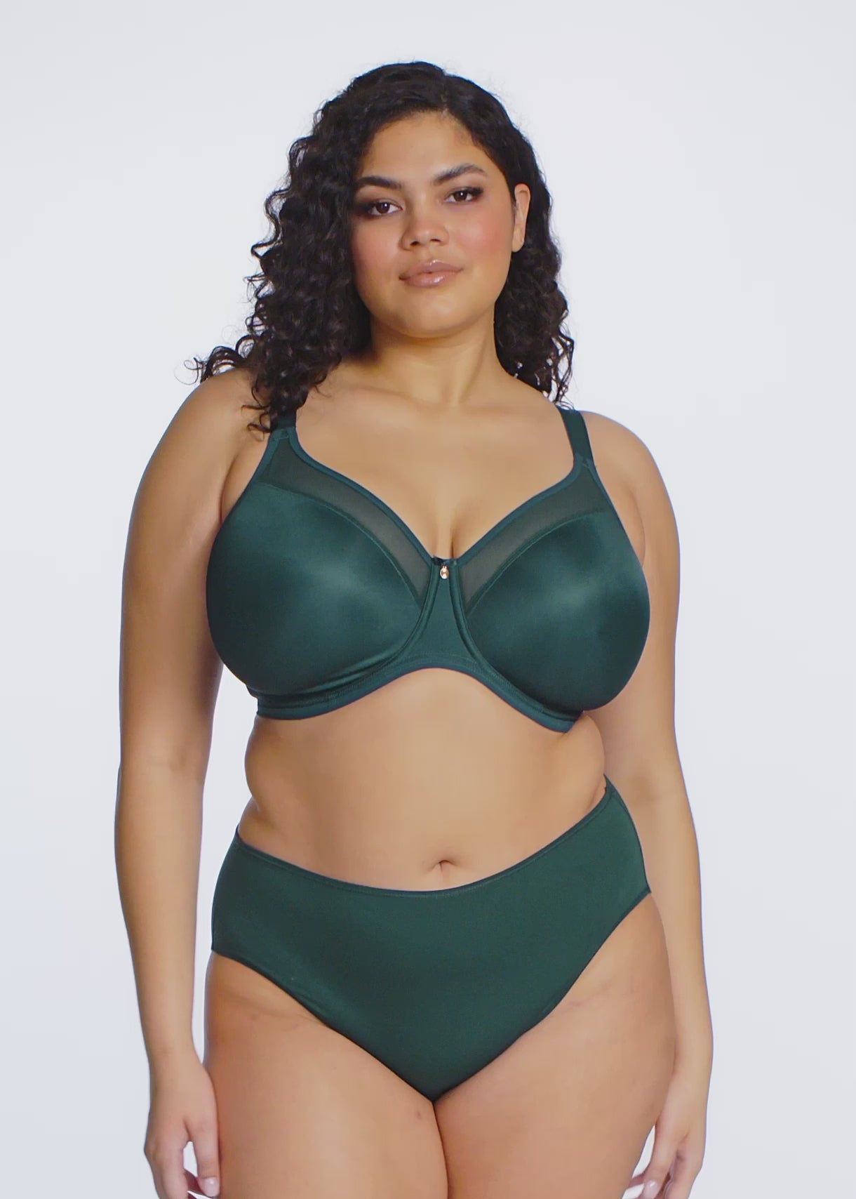 curvy woman wearing an emerald green lingerie set against a white background