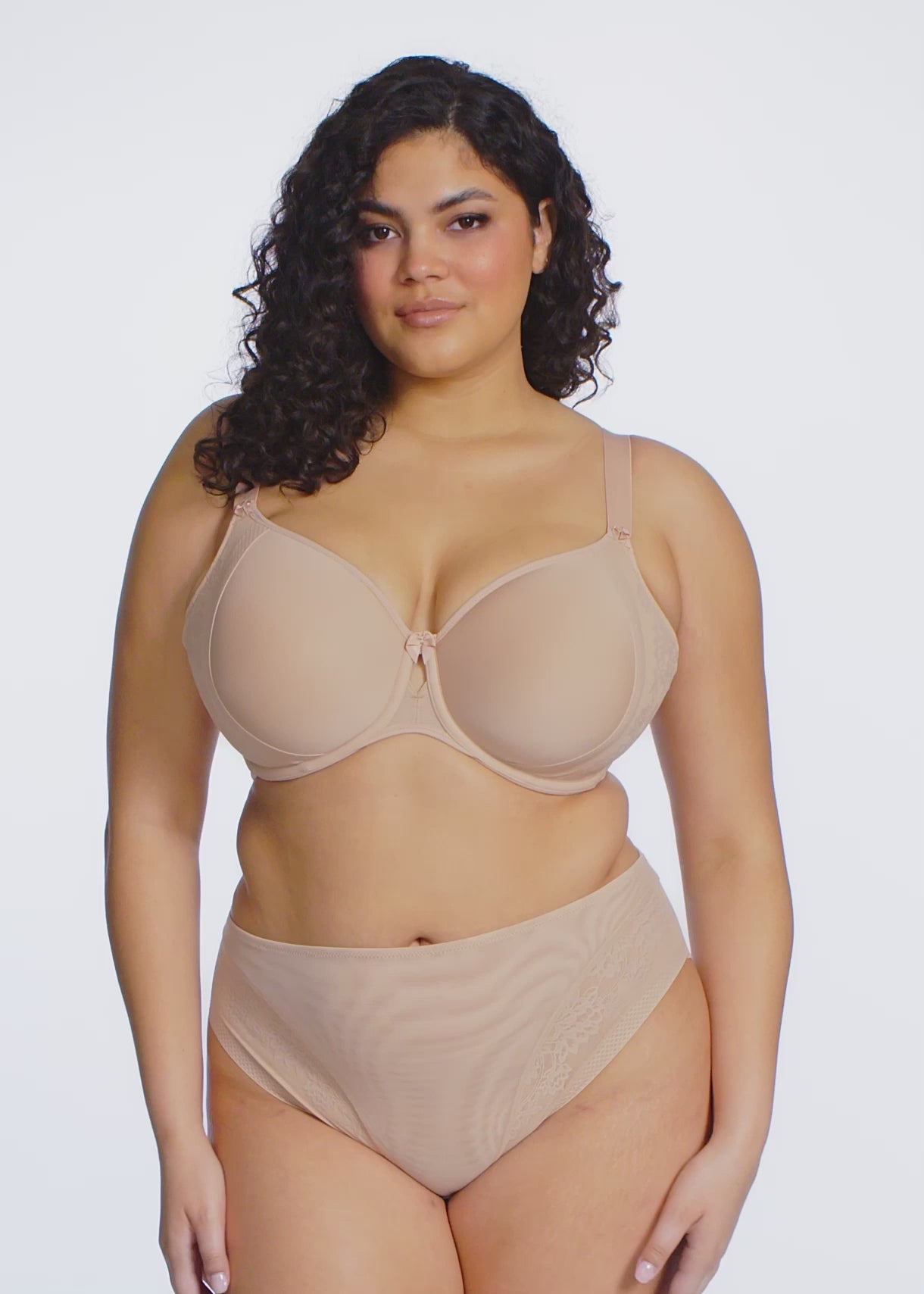 Curvy woman wearing beige lingerie against a white background