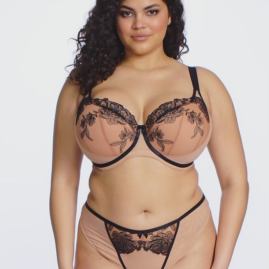 curvy Woman wearing a beige and black lace lingerie set on a white background