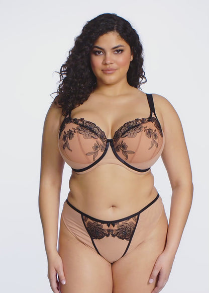 curvy Woman wearing a beige and black lace lingerie set on a white background