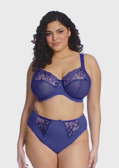 curvy woman wearing a Sapphire blue bra with floral lace details on a white background