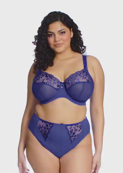 curvy woman wearing a Sapphire blue bra with floral lace details on a white background